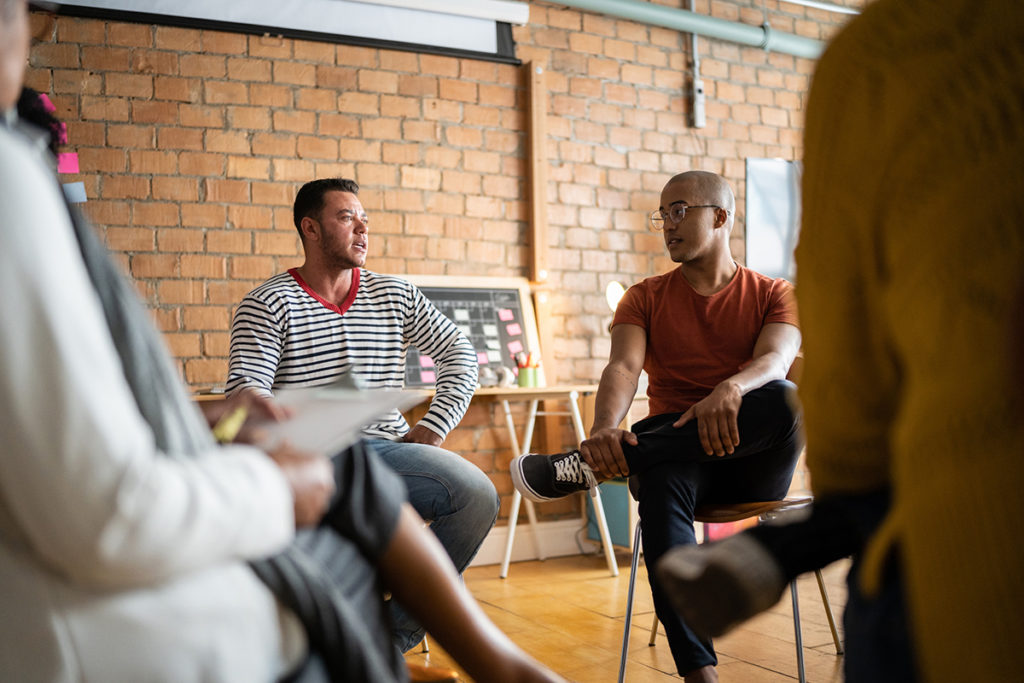 Transgender mature man talking in group therapy at a coworking