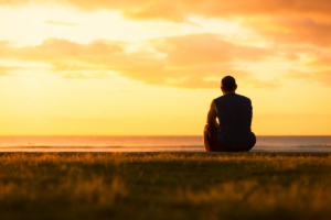 a man facing the ocean during sunset thinking about why he keeps on relapsing