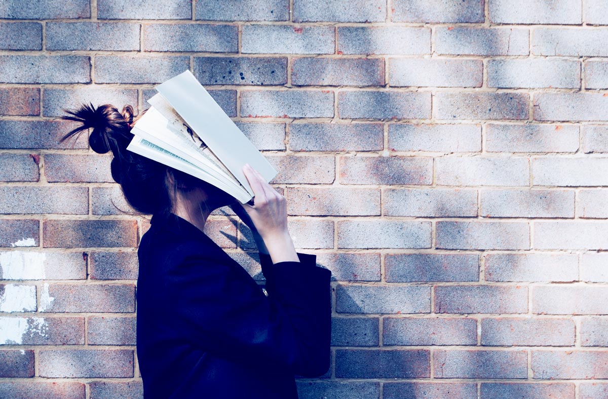 a woman hiding her face with a book