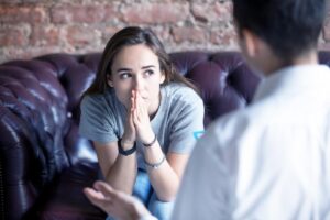 A young woman listens intently to her counselor during a one-on-one therapy session, finding a safe space to discuss her mental health and addiction recovery challenges.