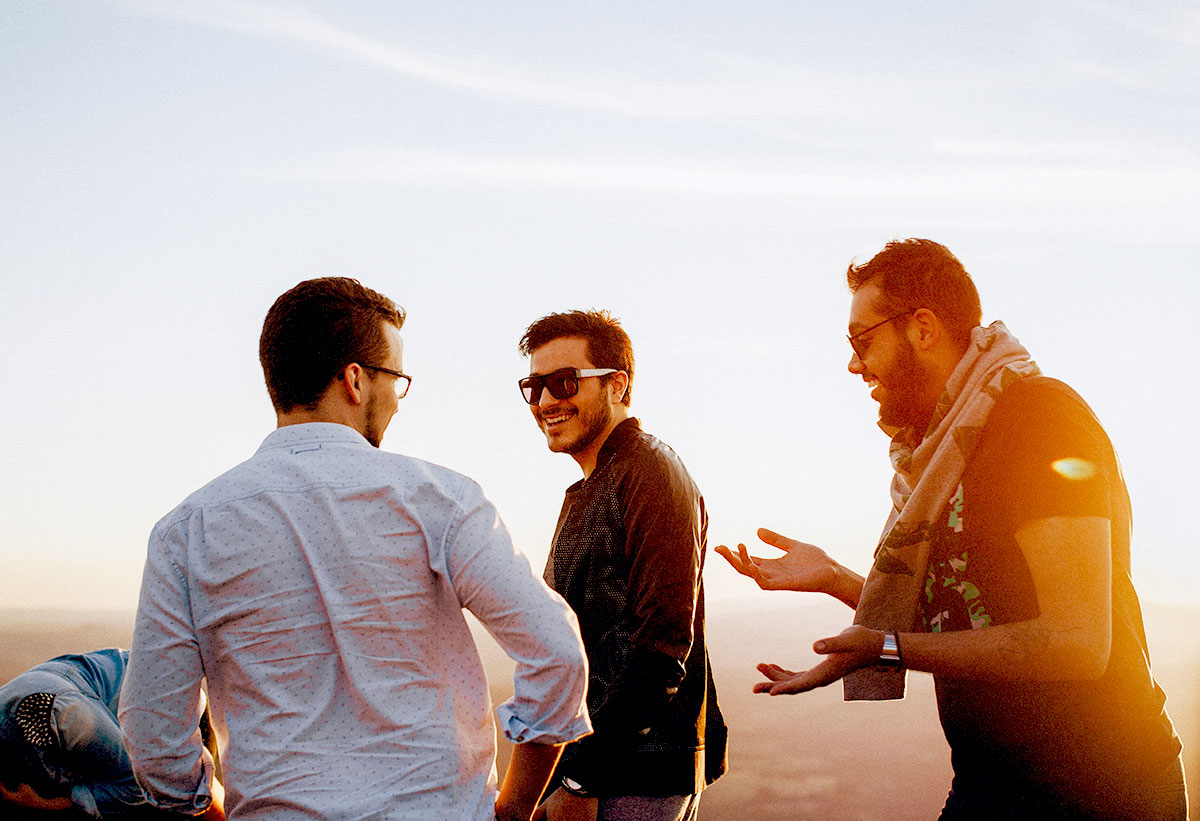 A group of men share a moment of laughter and genuine connection, illustrating the power of building healthy friendships and a strong peer support network for men's mental health and addiction recovery.