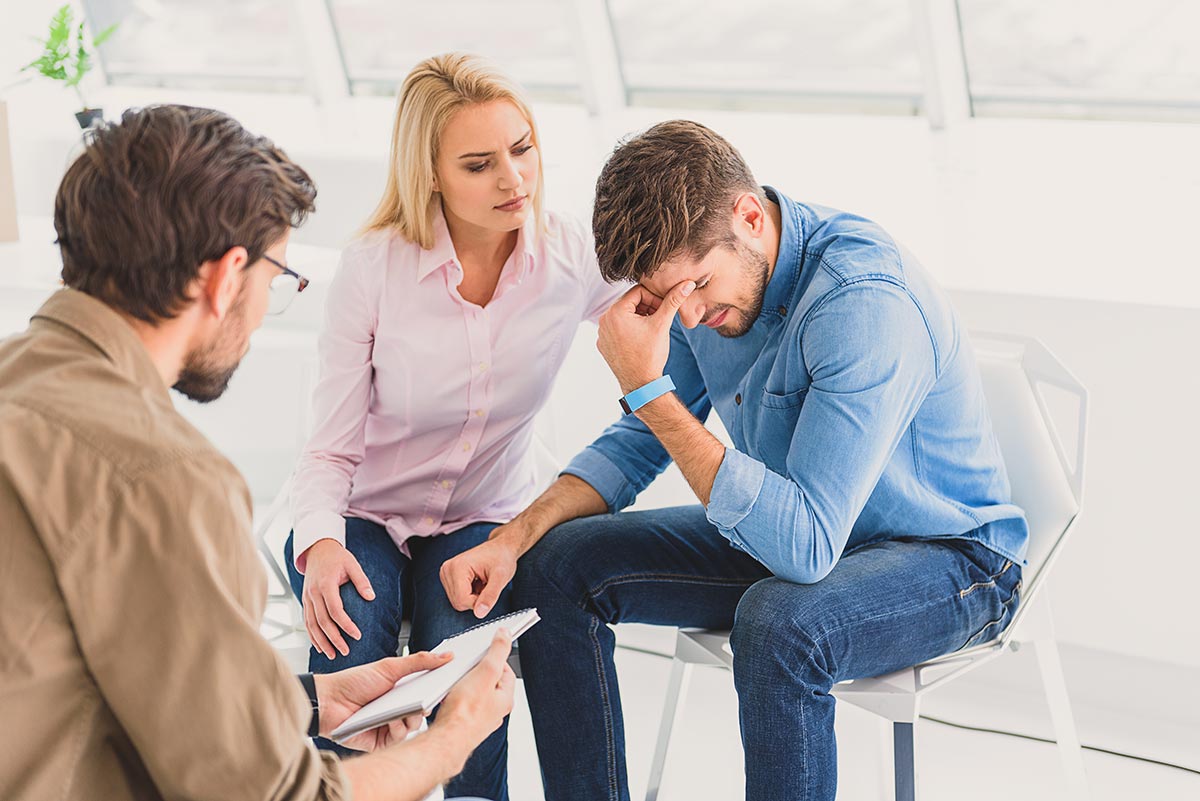 A woman provides compassionate support to a man struggling with his mental health, symbolizing the importance of empathy and professional help in navigating difficult times.