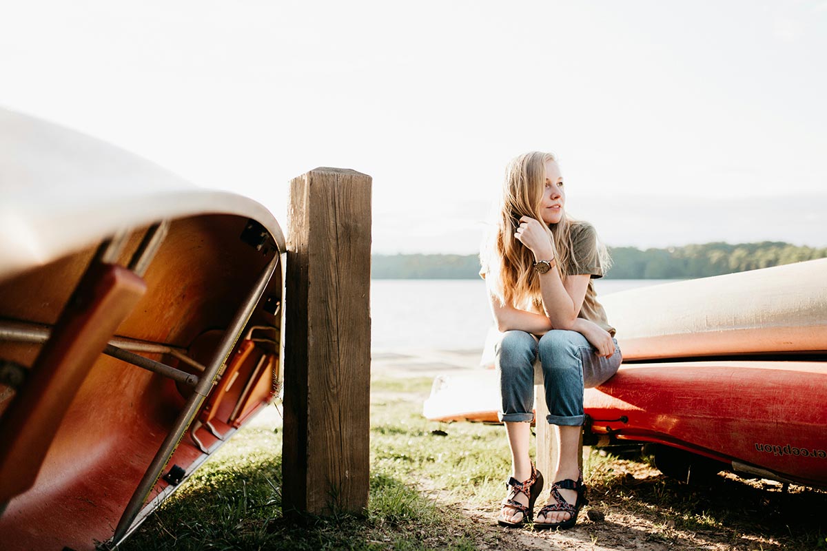 a lady sitting near a lake enjoying the warm weather