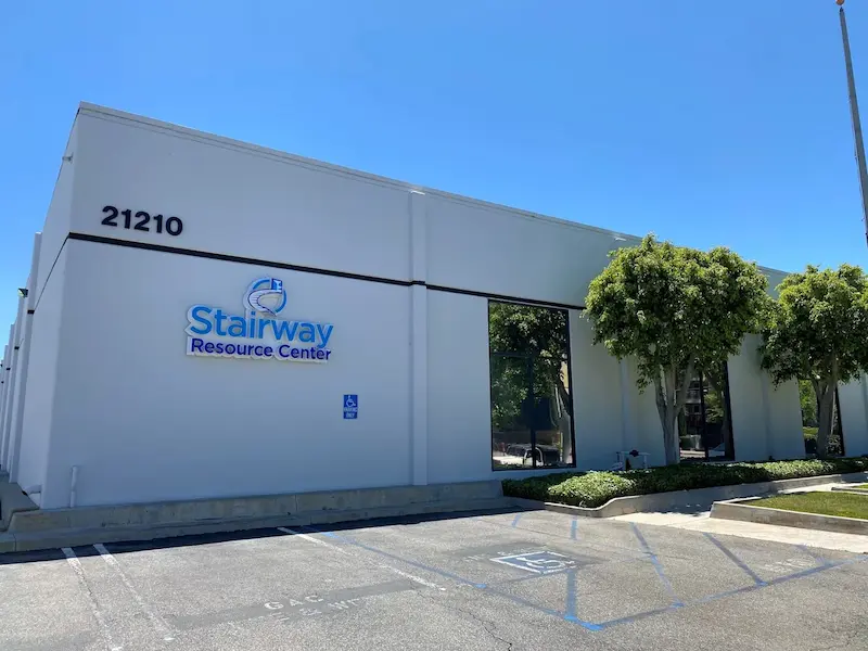 Exterior view of the Stairway Resource Center facility featuring the organization's logo mounted on a white commercial building.